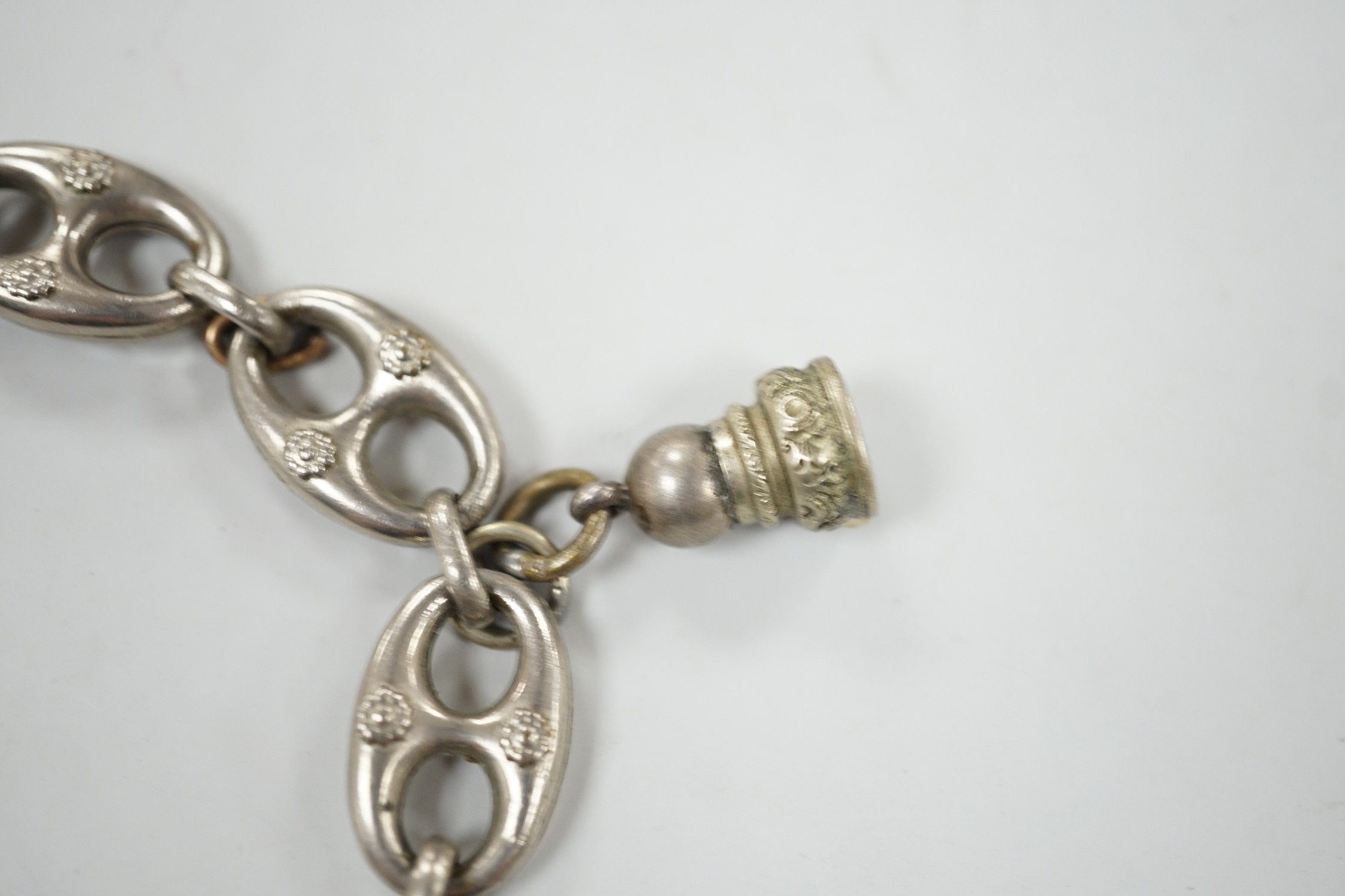 A white metal oval link bracelet, hung with three charms, including two fob seals, 21cm.